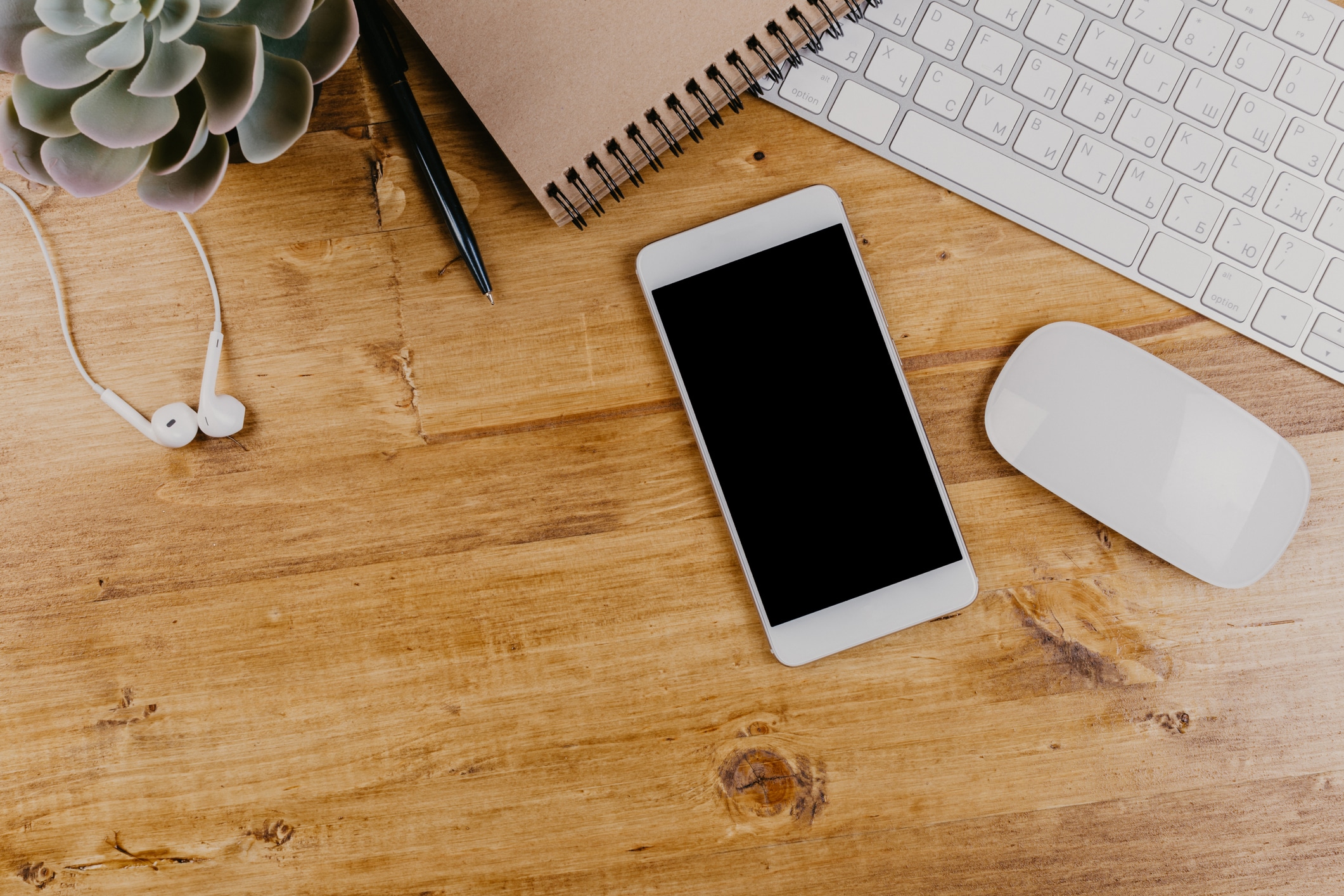 Trendy wooden Office Desk with keyboard, white earphones and office supplies