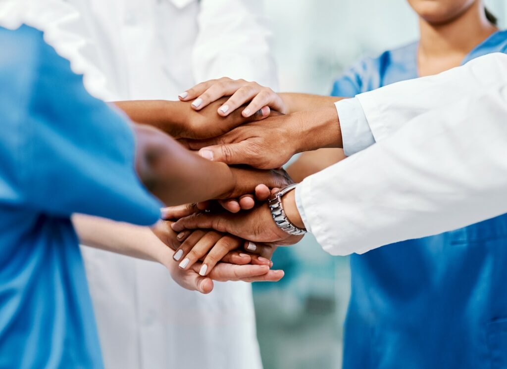 Doctors, nurses, and other healthcare employees putting their hands in a circle