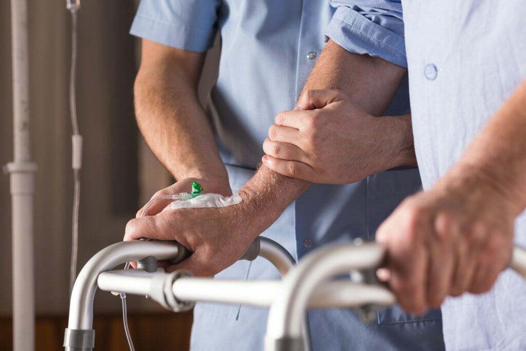 Hospital employee helping patient use walker