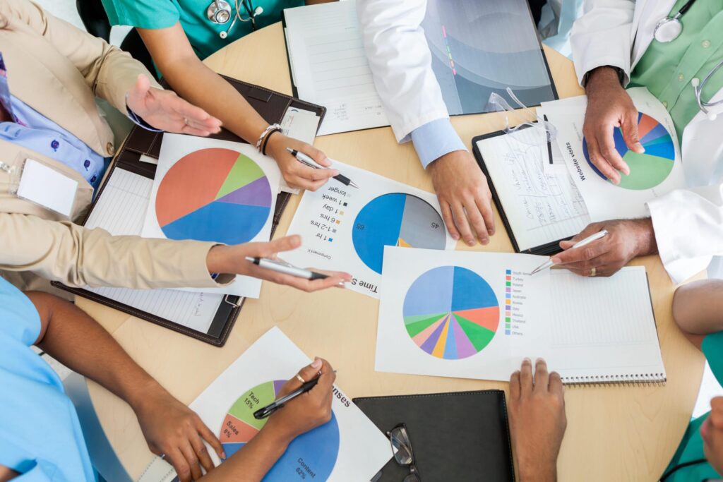 High angle view of medical staff meeting with hospital administrators and communicating data during hospital finance meeting.