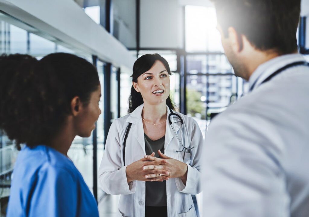 Healthcare organization leader talking to two employees about better engaging with employees