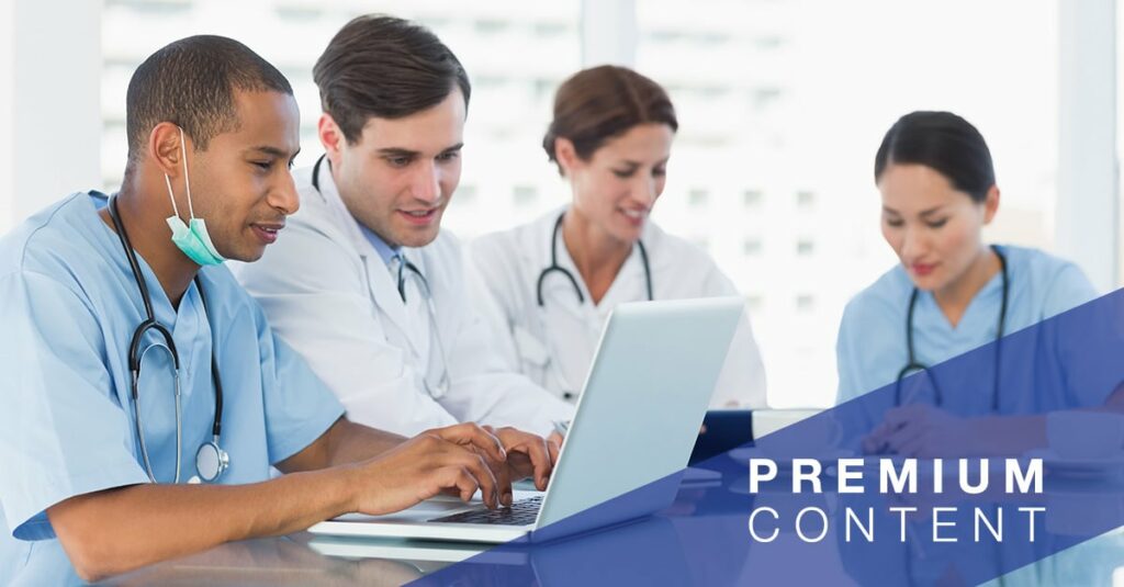 Multiple healthcare employees sitting at a table with two employees using a laptop