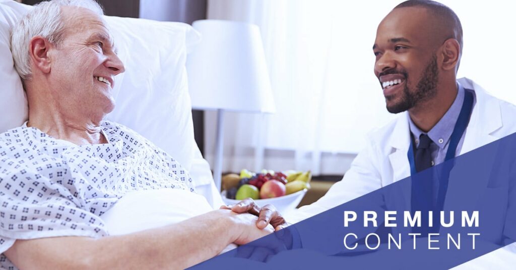 Doctor smiling as he sits at the bedside and grabs the hand of a patient