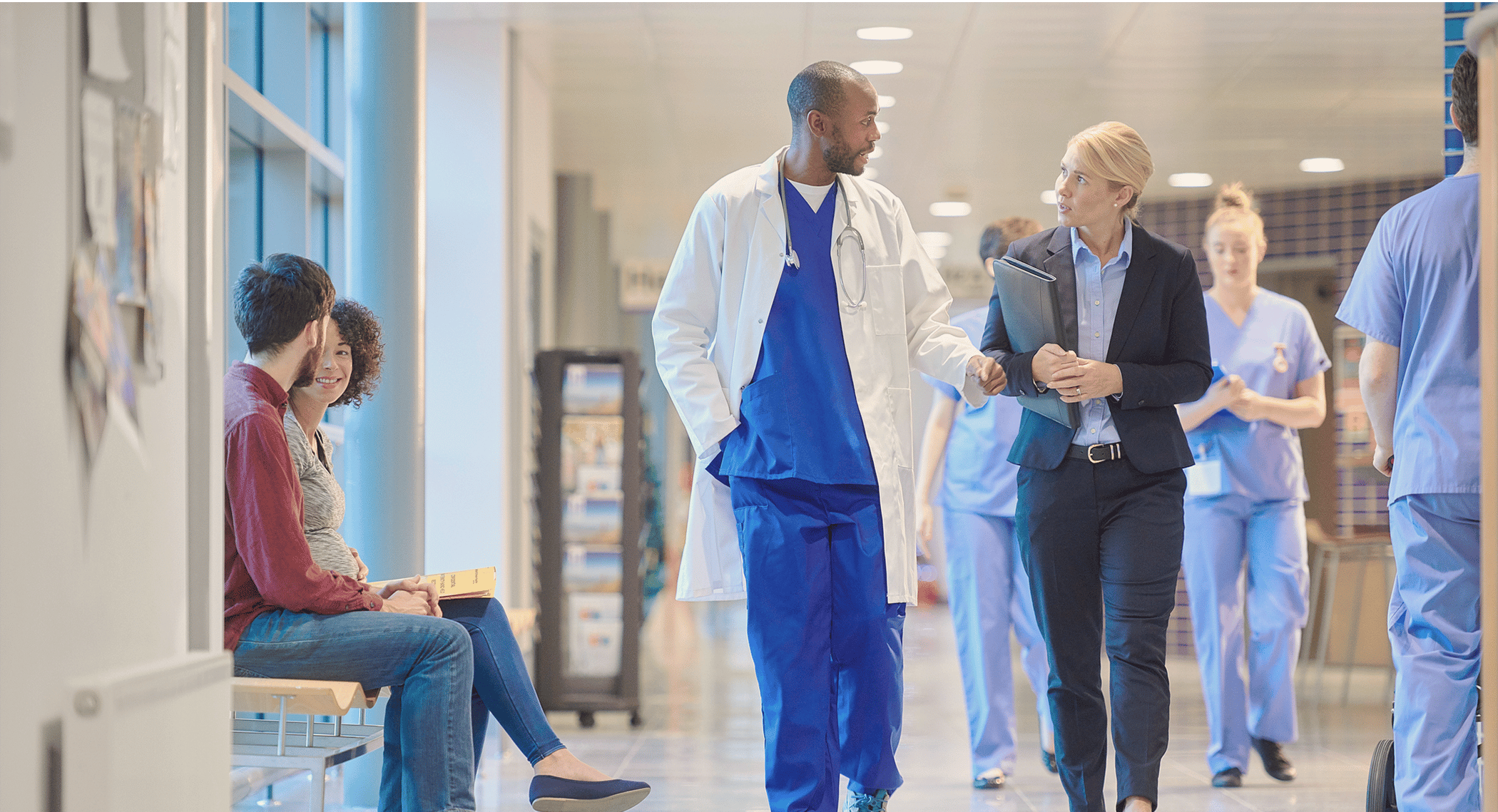 Doctor and healthcare consultant speaking while walking down hospital hallway