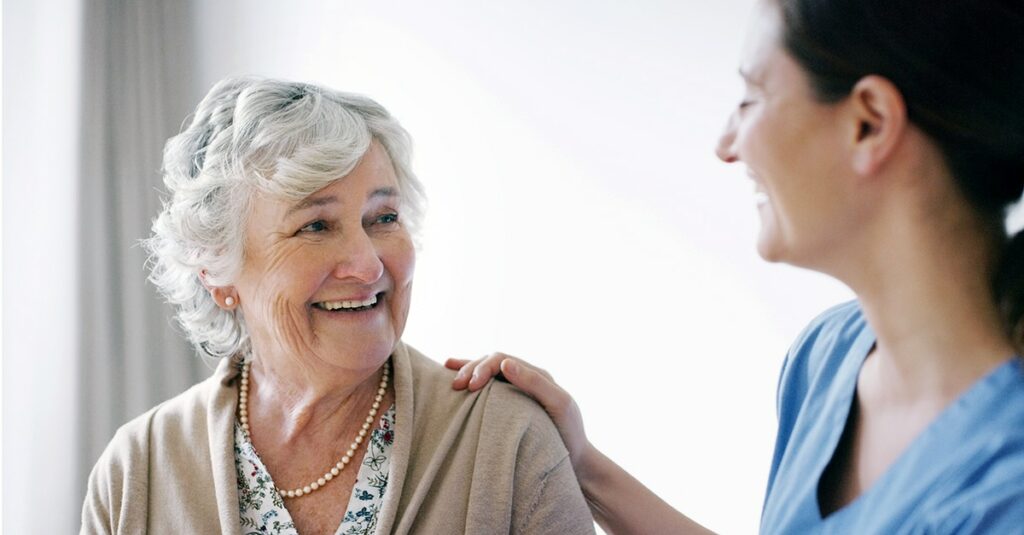 Happy senior woman being cared for by a young nurse in a retirement home