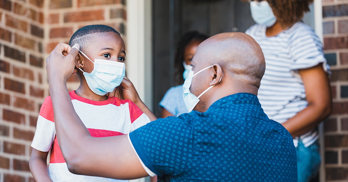 Father putting mask on child during the COVID-19 Health Crisis