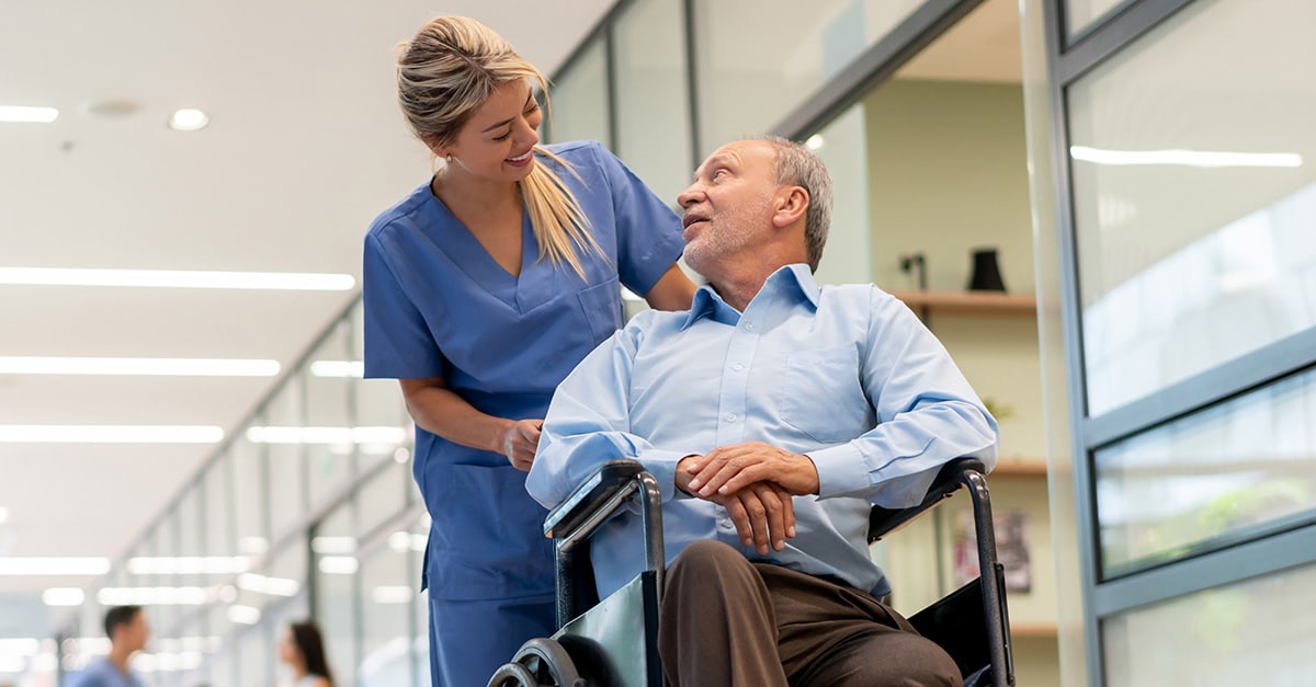 Nurse pushing patient in wheelchair while talking to patient