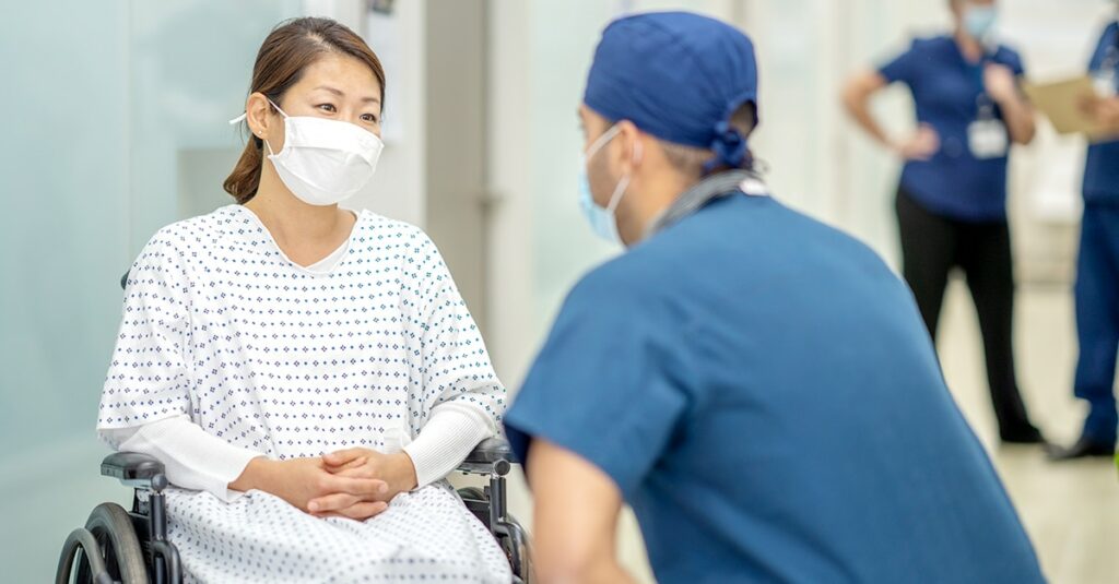 Nurse talking to patient in wheelchair during COVID-19 Pandemic