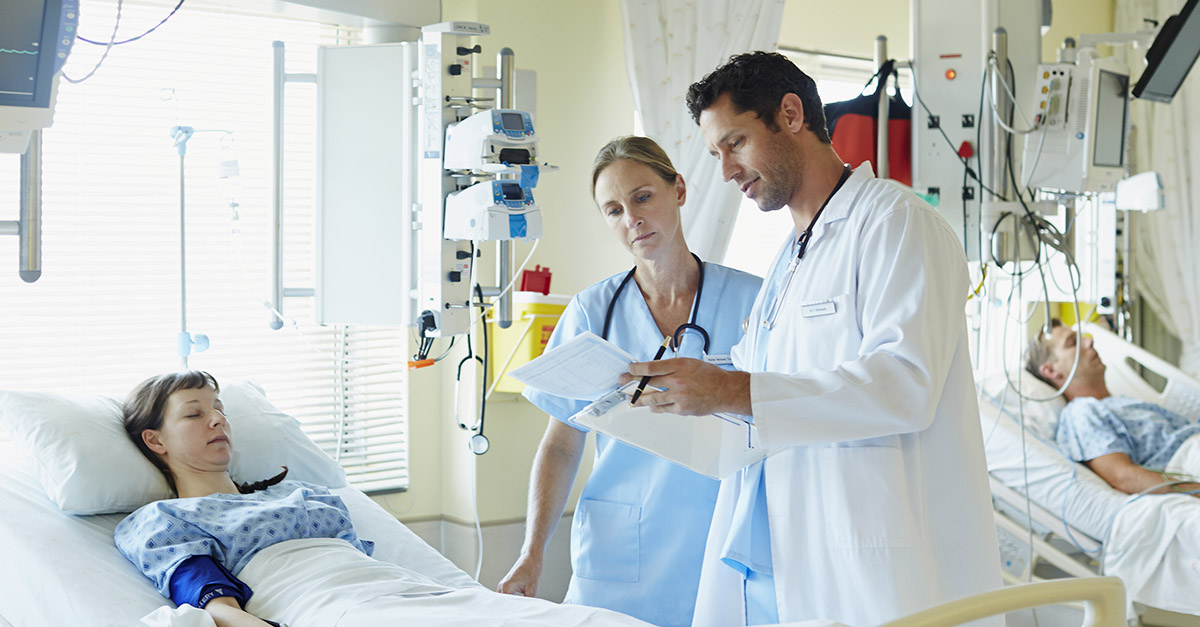 Doctor and nurse reviewing patient information in a hospital bed