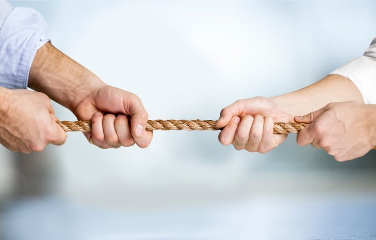 Business people pulling rope in opposite directions at office