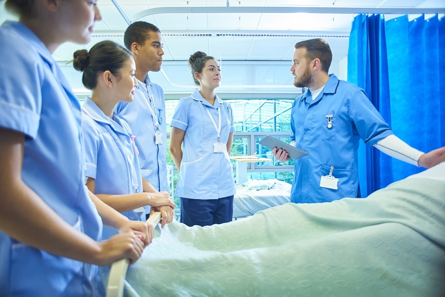 Group of nurses gathered around hospital bed