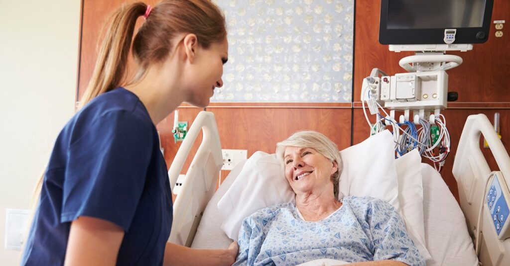 Nurse Talking To Senior Female Patient In Hospital Bed