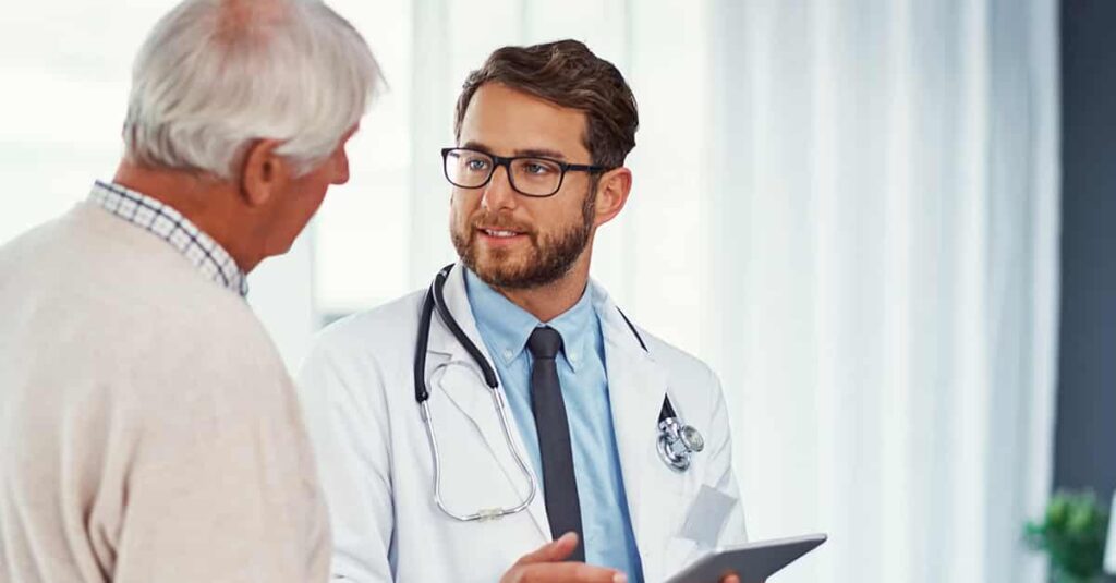 Doctor discussing something on a digital tablet with a senior patient in a clinic