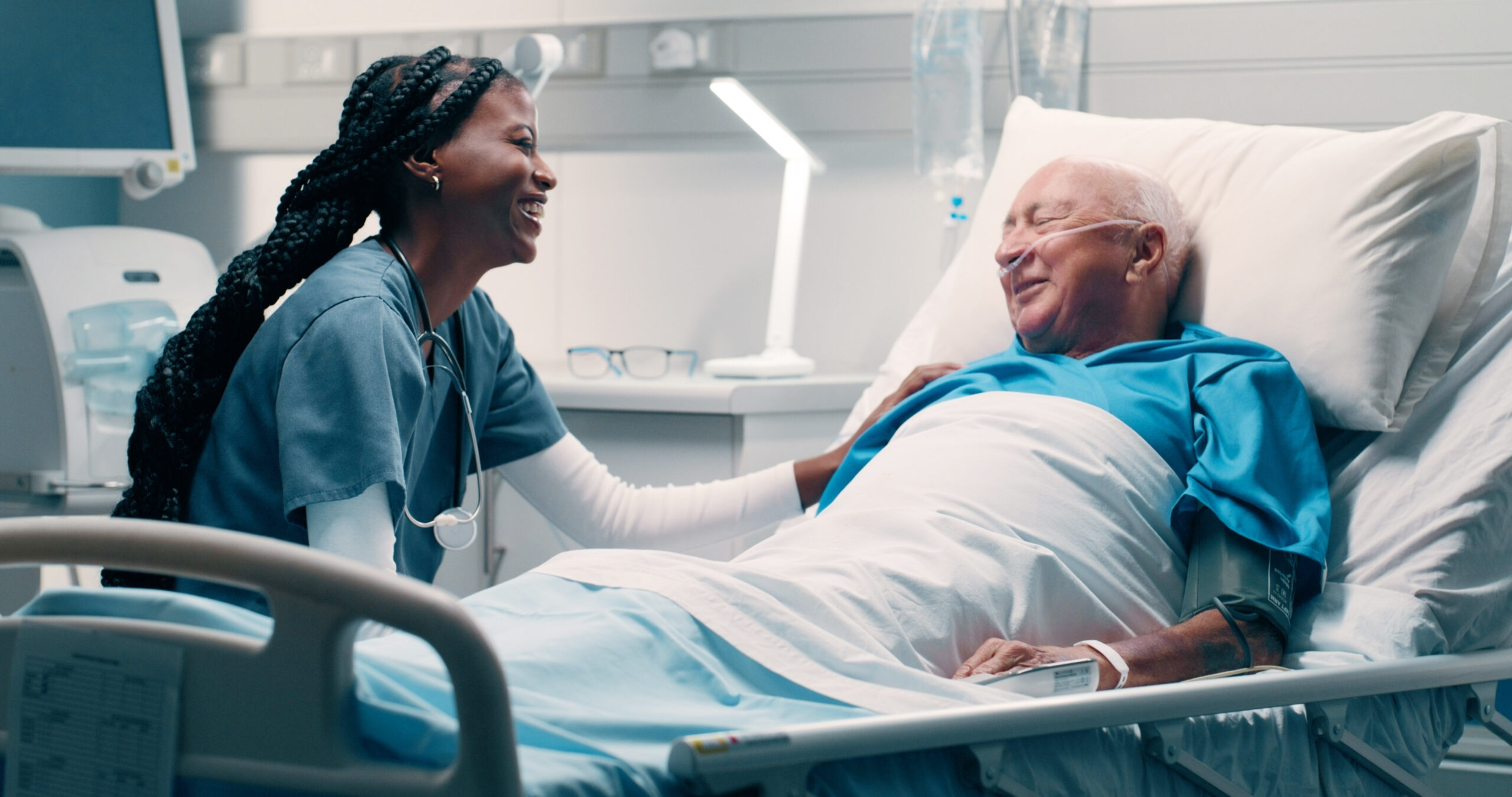 Nurse caring for patient in hospital bed.